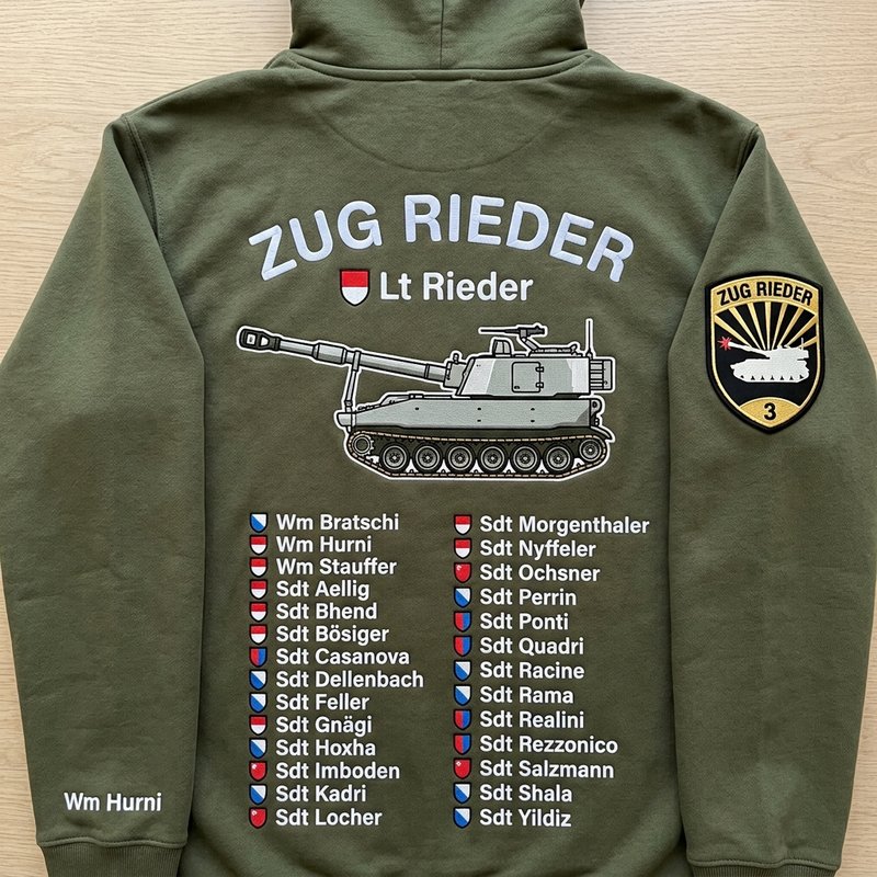 Rücken eines olivgrünen Premium-Hoodies «Zug Rieder» mit gesticktem Panzer-Motiv, Kantonswappen bei jedem Namen und gesticktem Badge am Arm