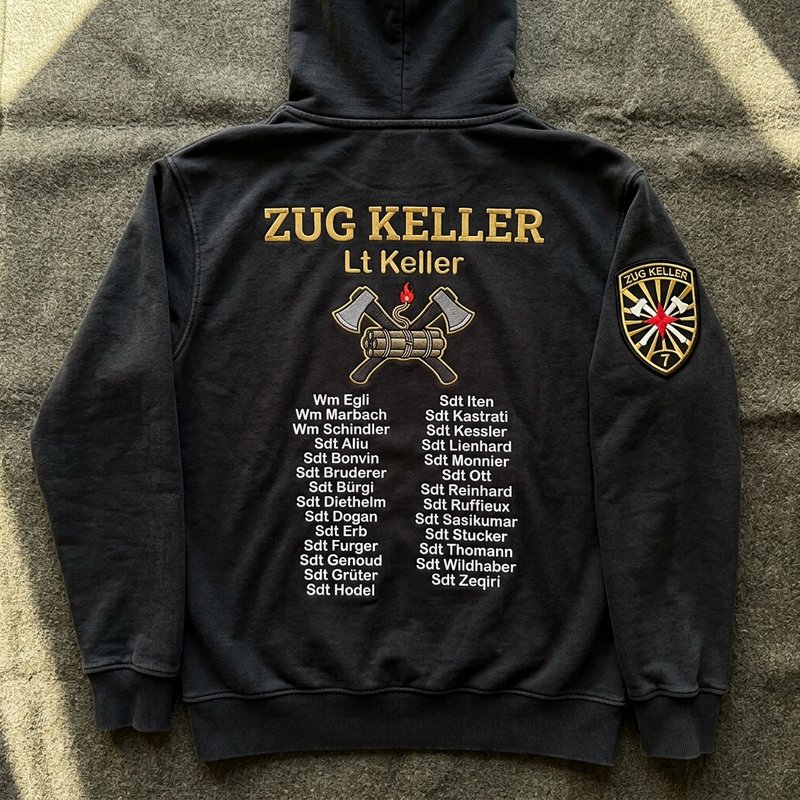 Rücken eines schwarzen Smart-Hoodies «Zug Keller», komplett gestickt mit Motiv und Namensliste, gestickter Badge am Arm
